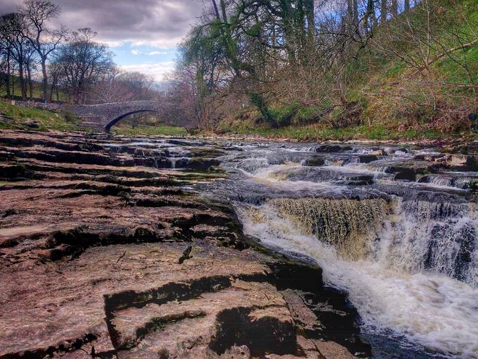 image of a classical british countryside, river with trees and stone bridge 